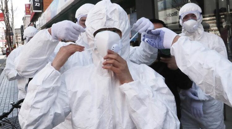 FILE - In this Feb. 27, 2020, file photo, a worker wears a face mask to spray disinfectant as a precaution against the coronavirus at a shopping street in Seoul, South Korea. As the coronavirus spreads around the world, International health authorities are hoping countries can learn a few lessons from China, namely, that quarantines can be effective and acting fast is crucial. On the other hand, the question before the world is to what extent it can and wants to replicate China’s draconian methods. (AP Photo/Ahn Young-joon, File)