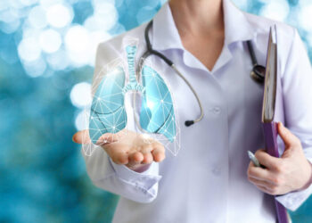 Doctor shows human lungs on blurred background.