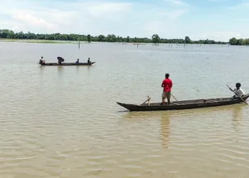 Majuli [Assam], Jul 14 (ANI): Locals make their way by boats through a flood-affected area as the water level of the Subansiri River rises due to the opening of NHPC Dam gates near the Majuli-Lakhimpur border, in Majuli on Tuesday. (ANI Video Grab)